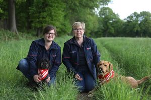 Zwei Helferinnen des BBD mit Hund in Dienstbekleidung und zusammen mit ihren Besuchshunden auf der Wiese.